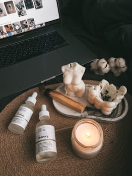A serene workspace featuring a laptop, candles, and skincare products for a relaxing atmosphere.
