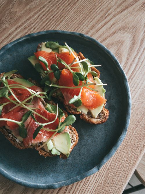 Free Close-up of nutritious avocado toast topped with salmon and sprouts on a ceramic plate. Stock Photo