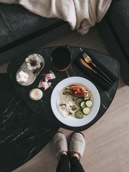 Flat lay of a cozy breakfast scene with vegetables and slippers, captured indoors from above.