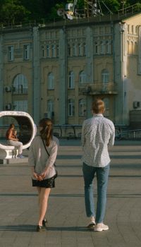A man and woman walk together on a Kyiv street, showcasing historic architecture.