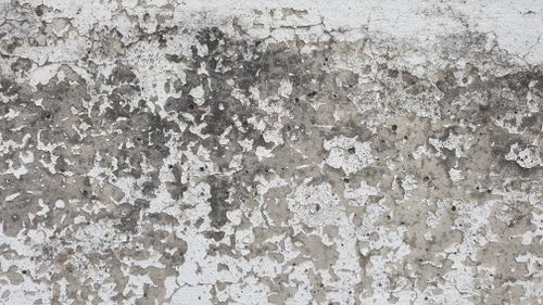 Free Close-up of a textured concrete wall with paint chipping and peeling, showcasing natural decay. Stock Photo