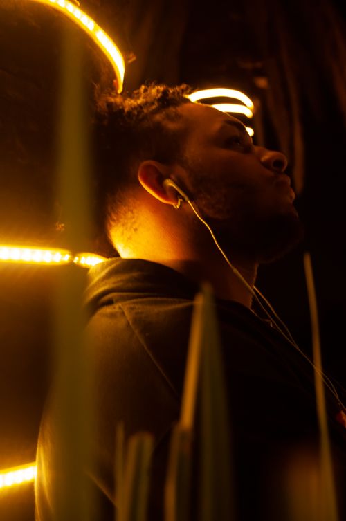 Free A thoughtful adult man listens to music with earphones against a warm, glowing background. Stock Photo