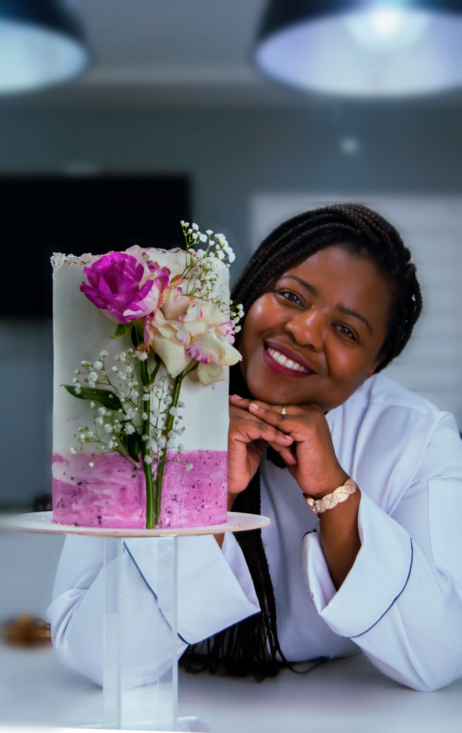 Woman cake maker smiling next to a decorated cake