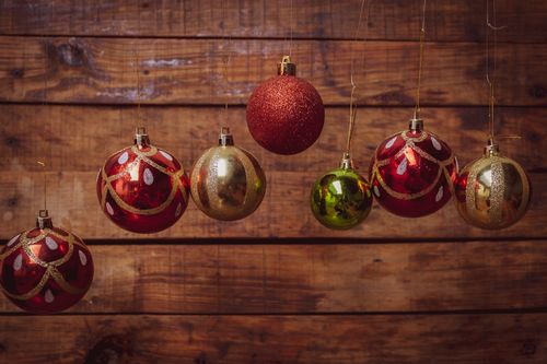 Free Colorful Christmas baubles hanging against a wooden backdrop, perfect for holiday decoration themes. Stock Photo