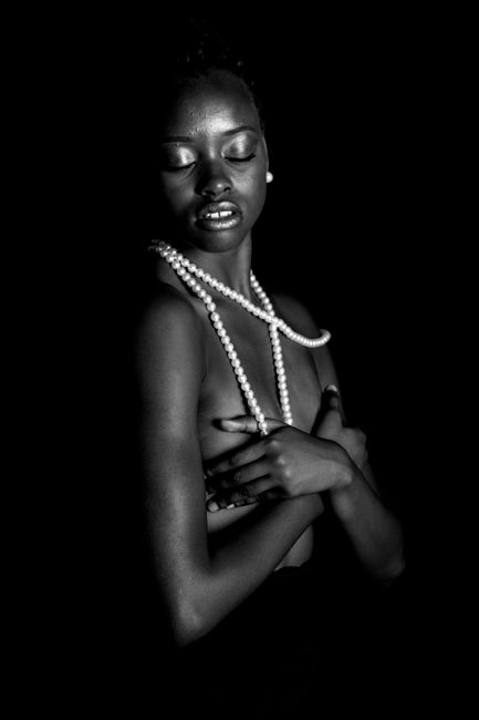 A striking black and white portrait of an African woman with a pearl necklace, embodying elegance and grace.