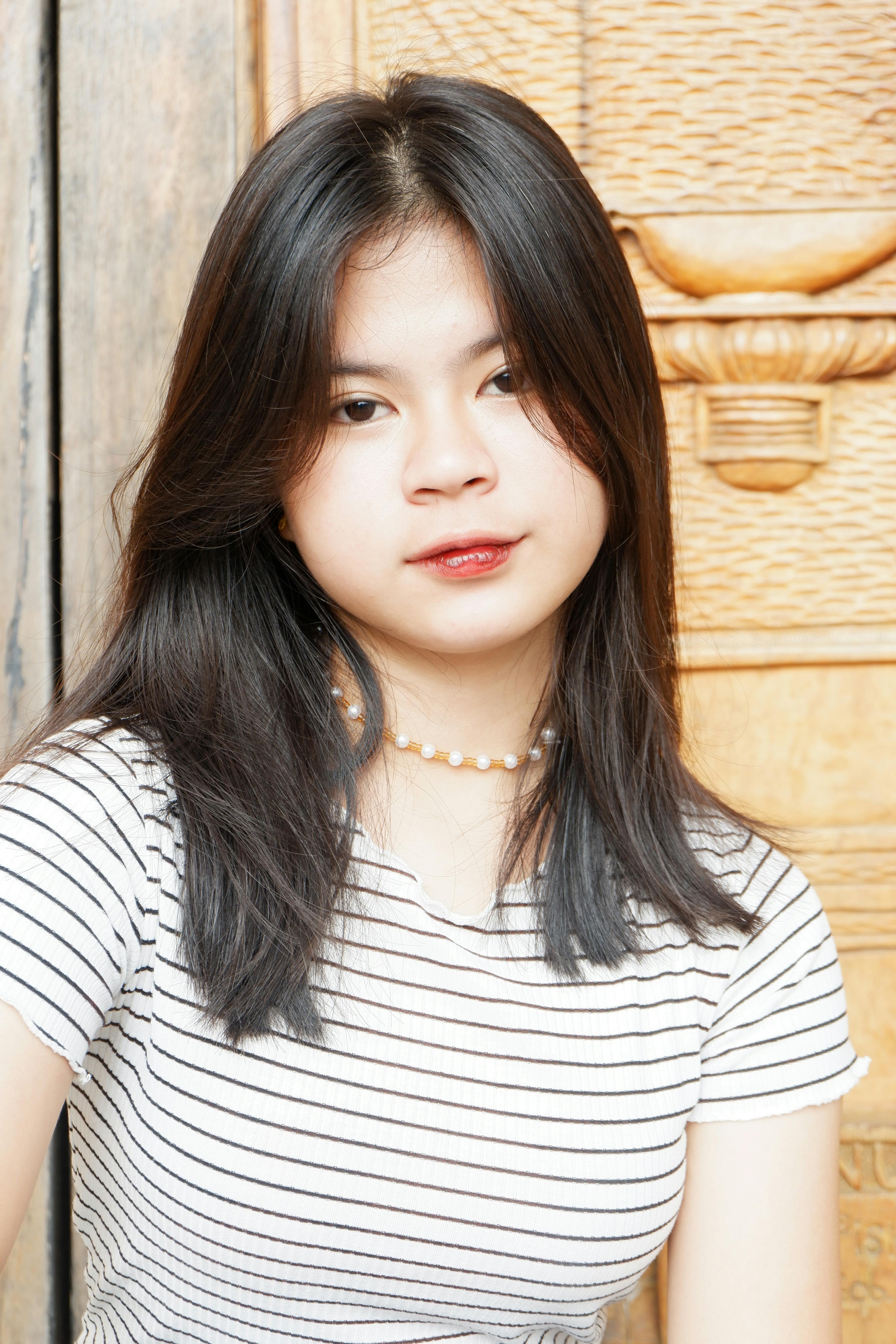Charming portrait of a young Asian woman with pearl necklace and striped shirt.