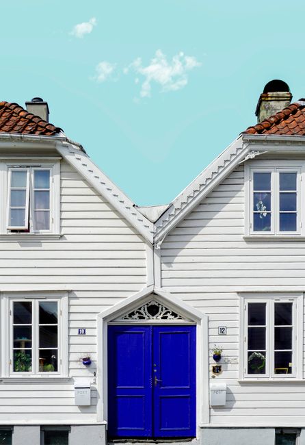White wooden houses with blue doors under a bright sky in Stavanger, Norway. Classic Scandinavian architecture.