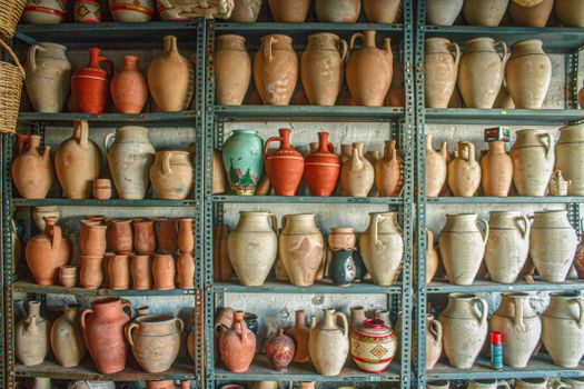 A variety of ceramic and clay jars displayed on industrial metal shelves. Ideal for craft references.