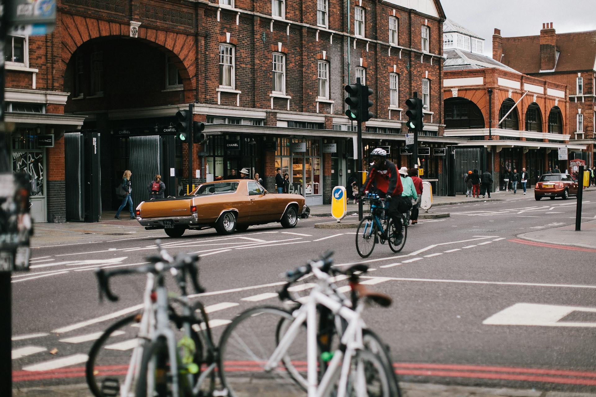 Cyclists navigate a busy intersection in Greater London with historic architecture.