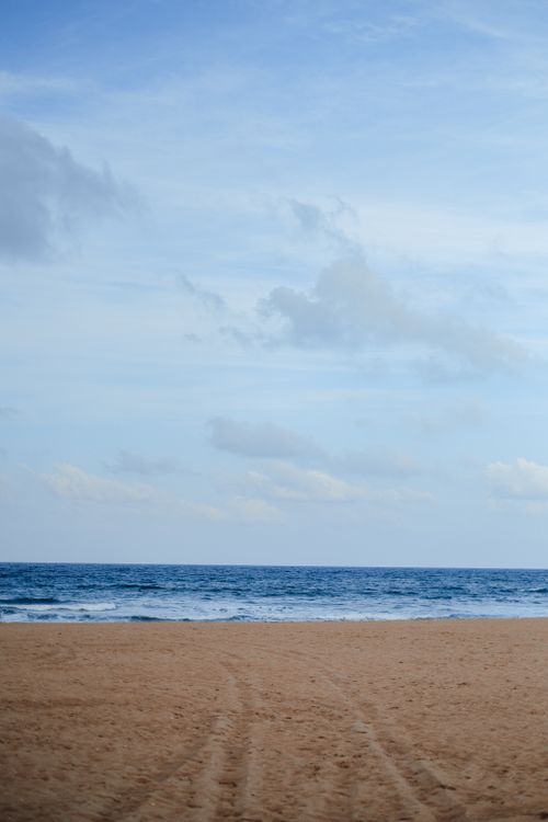 Free Peaceful beach with clear sky and calm ocean. Ideal for summer vacations. Stock Photo