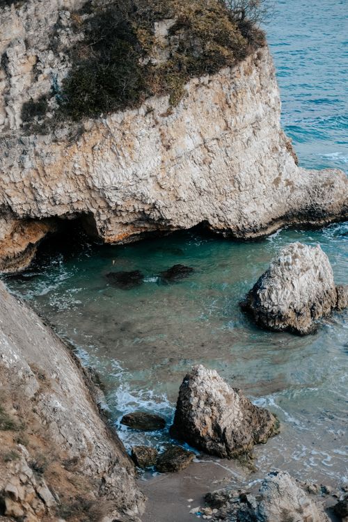 Free Dramatic cliffside view with turquoise sea and rocky shore, perfect for a serene escape. Stock Photo