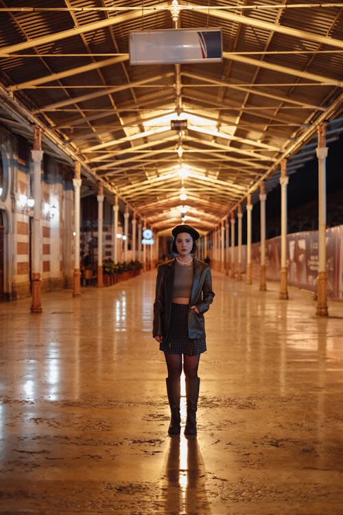Woman Standing on a Train Platform under Its Illuminated Roof