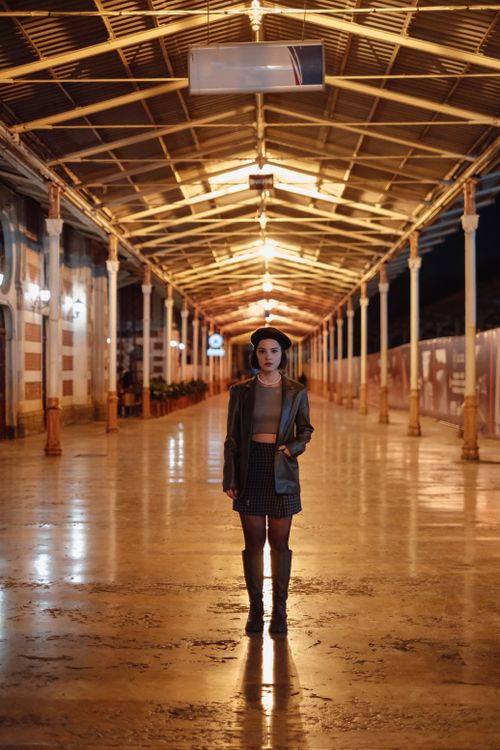 Free Fashionable woman in urban setting with warm lighting, wearing a beret and coat. Stock Photo