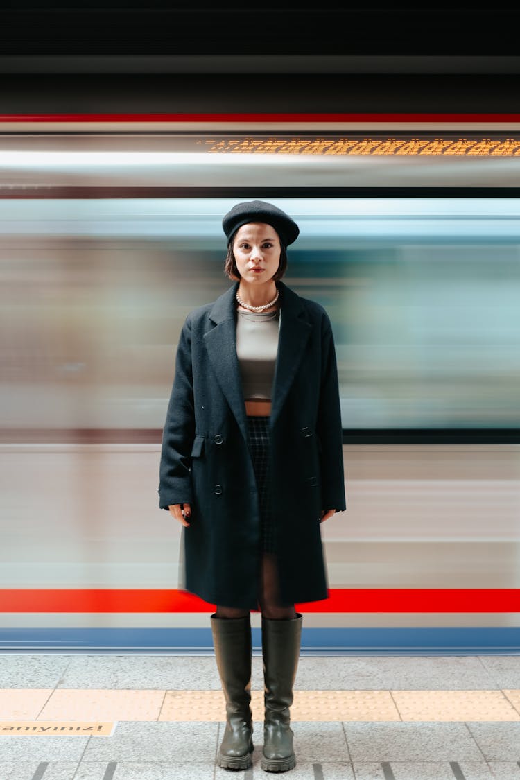 Blurred Train Behind A Woman In A Coat And A Beret