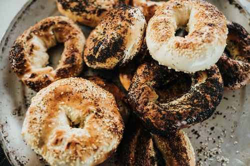 Free Delicious assortment of poppy and sesame seed bagels on a rustic platter. Stock Photo