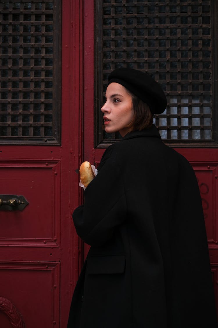 Woman In A Coat And A Beret Standing By A Door