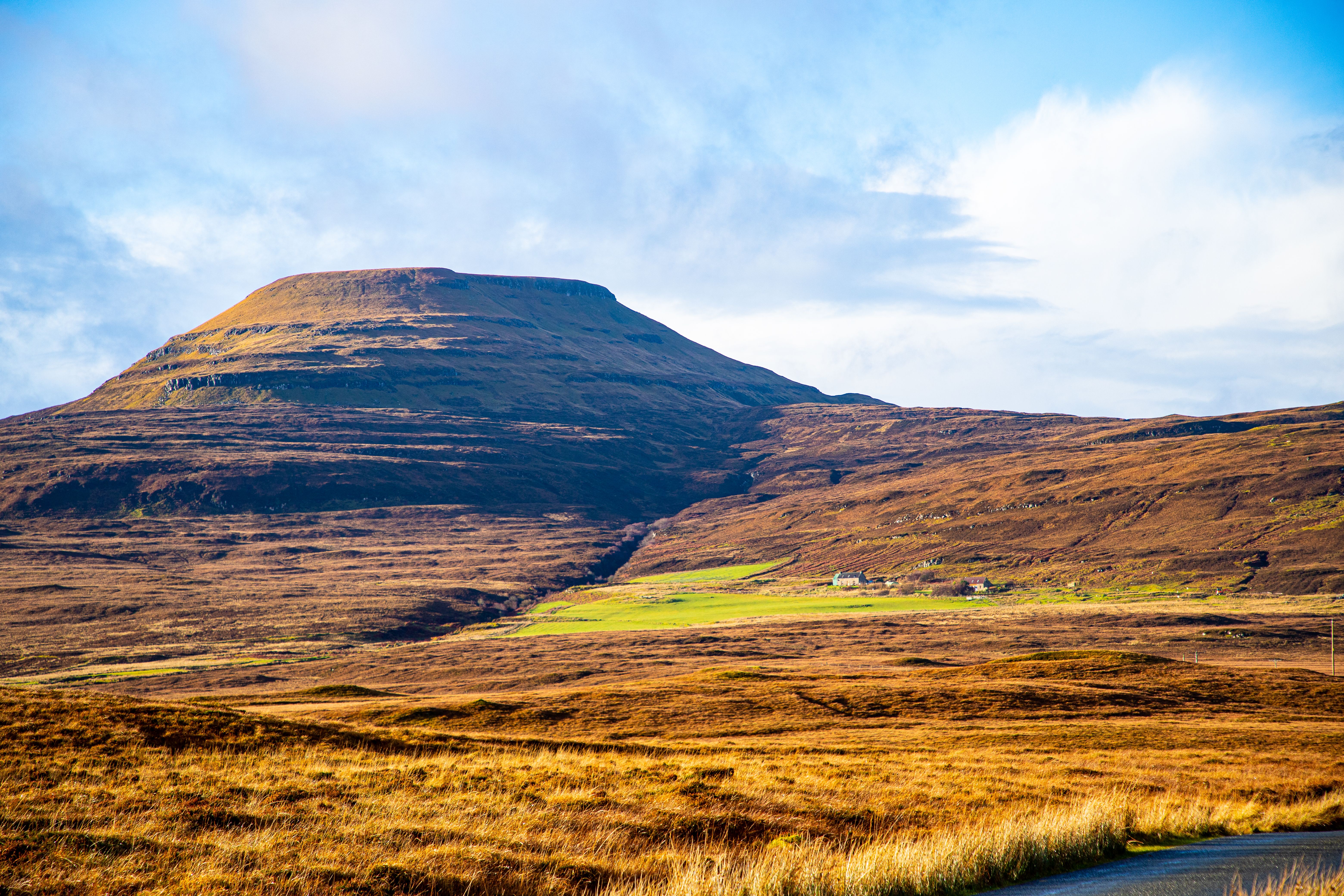 Captivating rural landscape featuring rolling hills and vast fields under a blue sky.