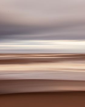 Blurred horizontal lines create an abstract desert landscape with sand and sky.