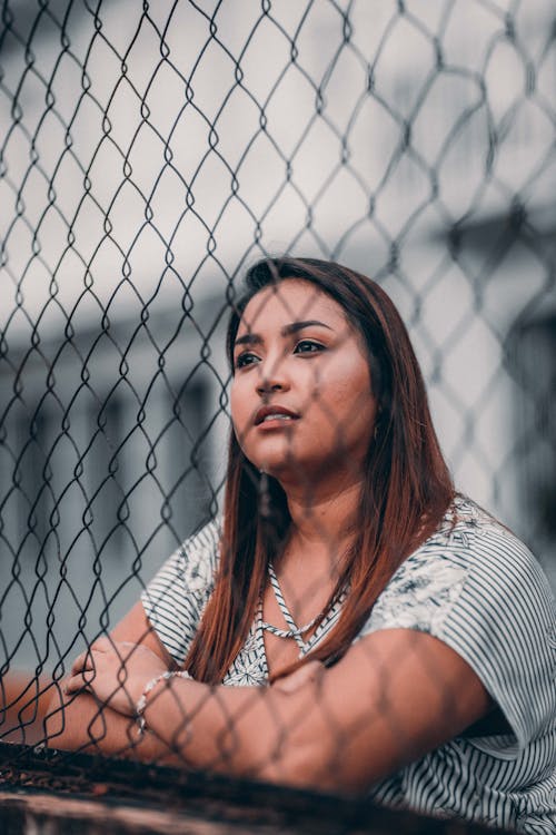 Shallow Focus Photography of Woman Leaning On Fence