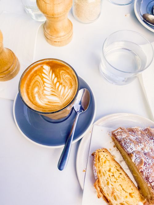 Free A delicious cappuccino with latte art served alongside a slice of pastry. Stock Photo
