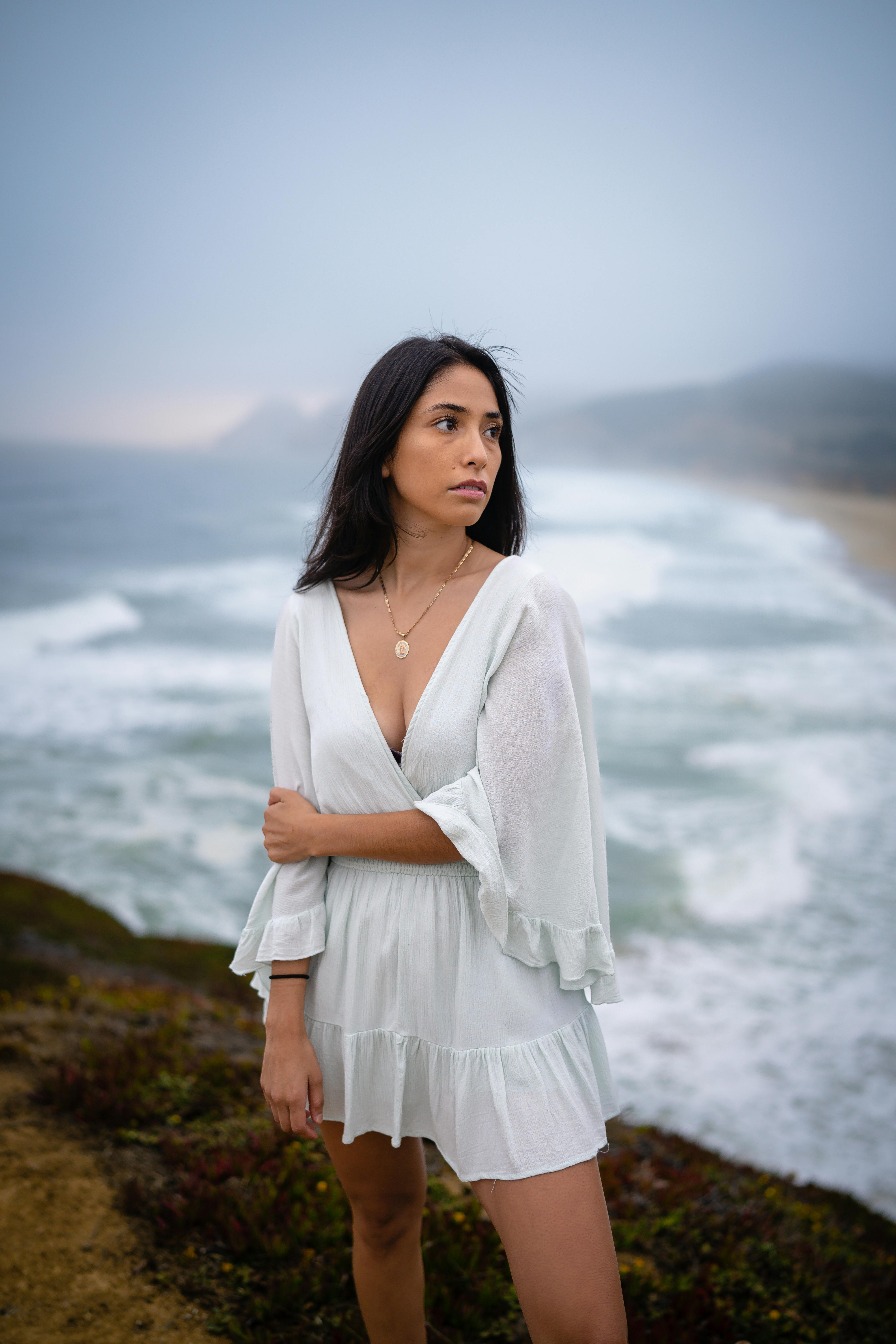 young woman in white mini dress standing on seashore