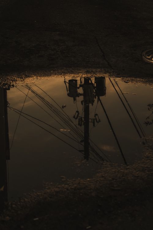 Free Reflection of utility poles in a puddle creates a moody urban atmosphere. Stock Photo