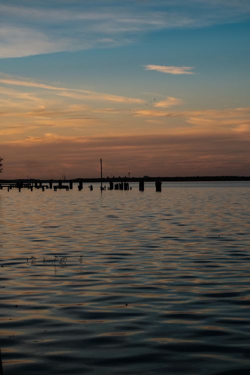 Free A peaceful ocean view at sunset with calm waters and vibrant sky hues. Stock Photo