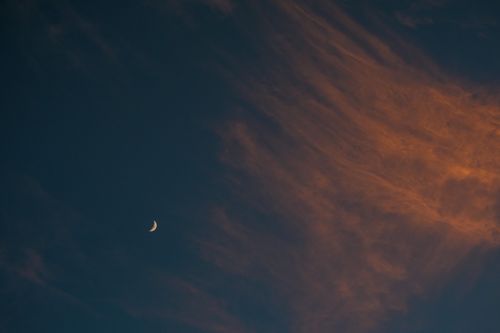 Free A beautiful crescent moon surrounded by stunning twilight clouds in a night sky. Stock Photo