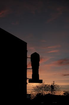 Silhouette of a cityscape at dusk with dramatic sunset colors in the sky.