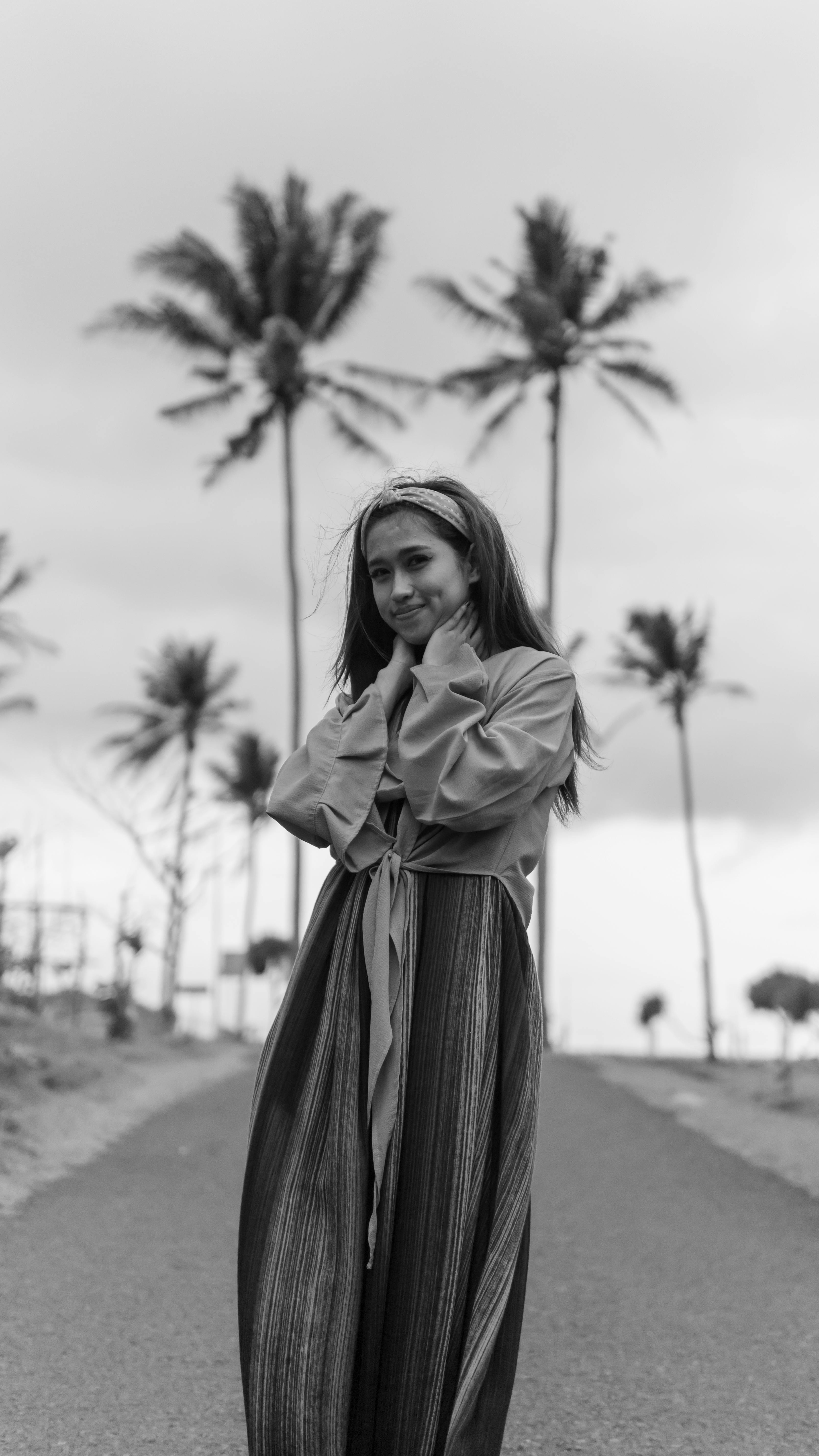 Black and white portrait of a woman in Bali surrounded by palm trees, exuding elegance and tropical vibes.