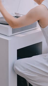 Person using a modern white record player with a minimalist design indoors.