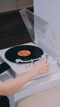 Close-up of a vinyl record being played on a modern turntable by a person indoors.
