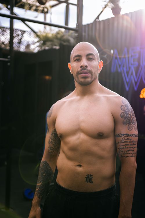 Free Shirtless muscular man with tattoos poses in daylight outdoors, showcasing fitness. Stock Photo