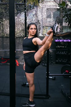 Woman performs an impressive leg stretch in a gym, showcasing strength and flexibility.