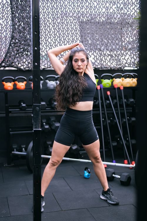 Free Athletic woman stretches in a vibrant gym setting, ready for workout. Stock Photo