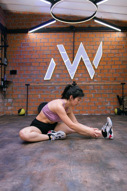 Femme effectuant des étirements au sol dans une salle de sport