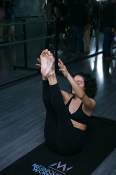 Woman practicing yoga in a modern gym, focusing on flexibility and balance with a seated forward bend pose.
