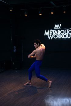 Energetic dancer performing shirtless indoors, showcasing muscular physique and agility.