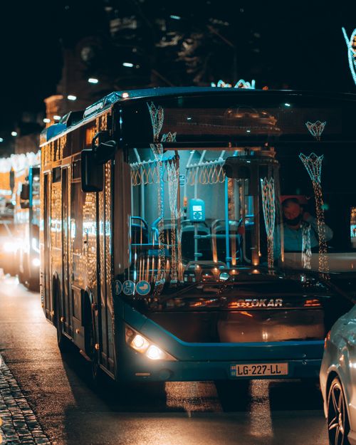 Free Buses adorn Kutaisi street at night, capturing urban transportation with festive lights. Stock Photo