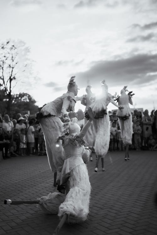 Black and White Photo of a Group of Performers Walking on Stilts