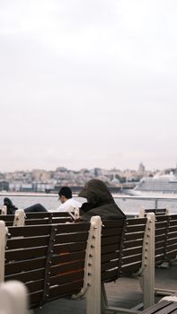People relaxing at a pier in Istanbul, Turkey, with cityscape view.