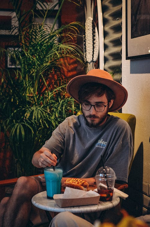 Man Wearing a Hat Sitting with Drinks at a Coffee Table