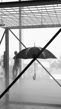 Black and white image of an artistic umbrella installation with raindrops and silhouettes.