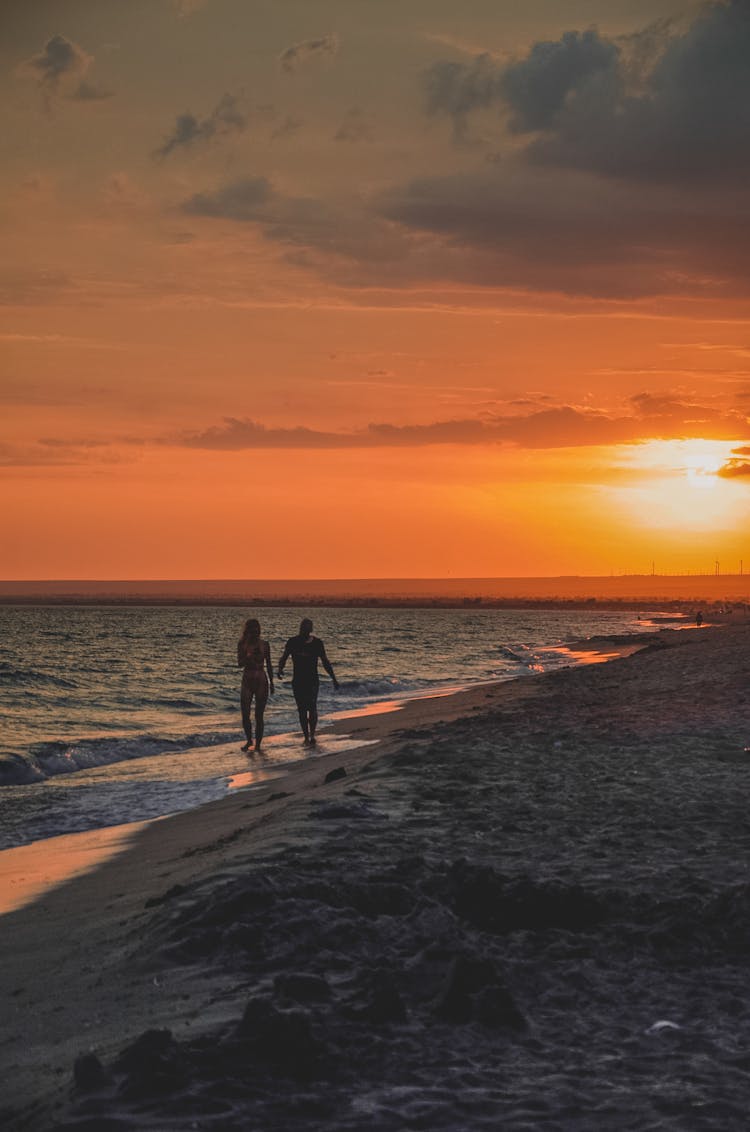 Couple Walking On Beach At Sunset