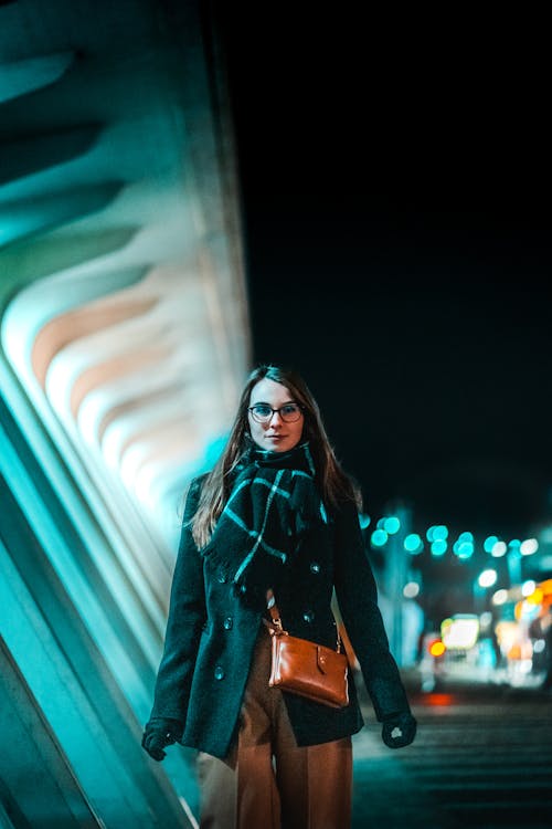 A Woman Wearing a Coat and a Scarf at Night