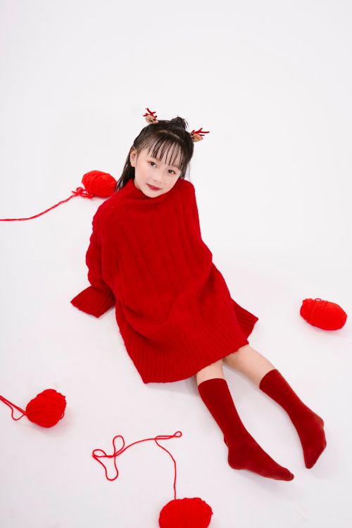 Free Asian girl in red sweater with yarn, studio shot. Fashionable and conceptual. Stock Photo