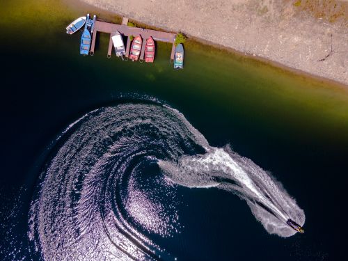 Free Aerial shot of boats moored alongside a speeding motorboat on a lake in Osikovo, Bulgaria. Stock Photo