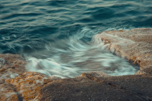 Free Dramatic scene of ocean waves crashing against rocks with swirling water patterns. Stock Photo