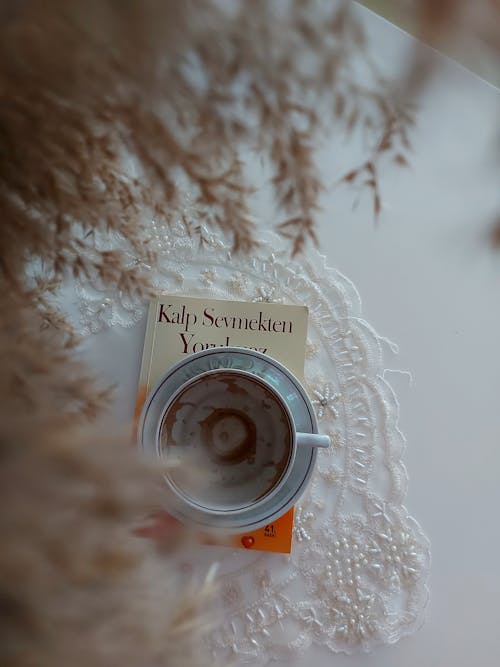 Top View of a Coffee Cup with a Book on a Table, and Dry Plant