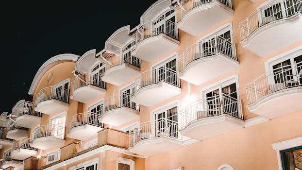 Low angle view of a modern building with balconies lit at night, showcasing architectural elegance.